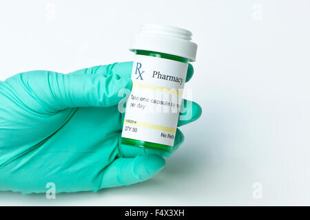 Krankenschwester mit behandschuhten Hand hält grünes Rezept Flasche. Stockfoto