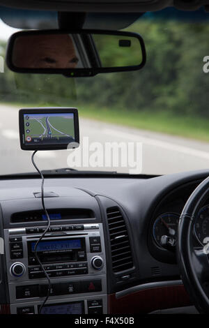 Männliche Fahrer mit einem Navi (Satelliten-Navigationsgerät) an einer Hauptstraße in UK Stockfoto