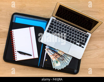 Betriebswirtschaftlicher Hintergrund - ausführliche Geschäftsfall mit Laptop, offene Notebook und US-Dollar/Euro-Rechnungen. Draufsicht der hölzernen Struktur des t Stockfoto