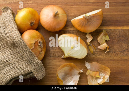 frische Zwiebeln in Jute Sack auf Holztisch Stockfoto