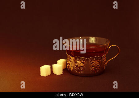 Tasse Tee mit Würfel Zucker im dunklen Raum Stockfoto