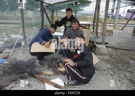 Idomeni, Griechenland. 23. Oktober 2015. Flüchtlinge posieren mit Maiskolben, die sie auf dem offenen Feuer gebraten haben. Tausende Flüchtlinge überqueren die Grenze zwischen Griechenland und Mazedonien täglich um die kleine griechische Stadt Idomeni, trotz der sich verschlechternde Wetter und starkem Regen. Hier nehmen sie einen kurzen Stopp für einige Vorräte und warten ihrerseits auf die Grenze zu überqueren. Bildnachweis: Michael Debets/Pacific Press/Alamy Live-Nachrichten Stockfoto