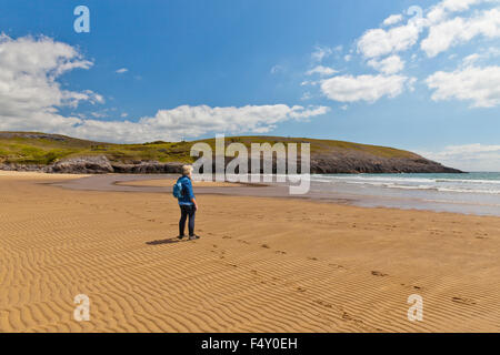 Eine weibliche Walker am einsamen Strand von Broadhaven, Pembrokeshire, Wales, UK Stockfoto