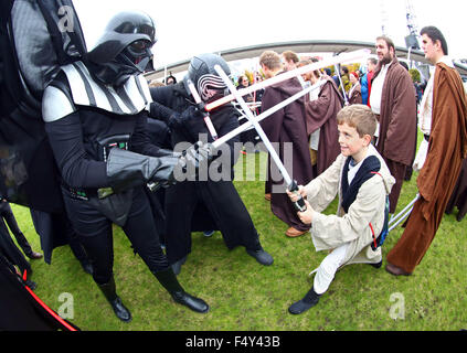 London, UK. 24. Oktober 2015. Darth Vader aus Star Wars nimmt auf einen jungen Jedi-Ritter in einem Lichtschwert-Kampf am MCM London Comic Con in Excel London Credit: Paul Brown/Alamy Live News Stockfoto