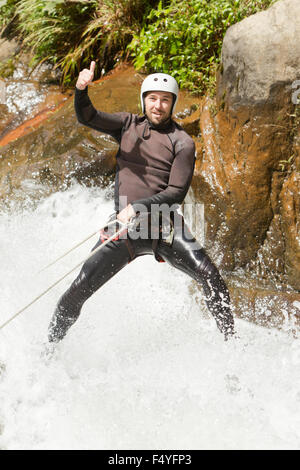 Erwachsene Mann Absteigend einer ecuadorianischen Wasserfall in die richtige Position Stockfoto