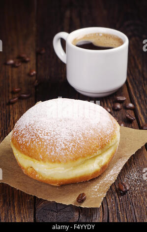 Berliner Krapfen mit Tasse heißen Kaffee auf dunklen Holztisch Stockfoto