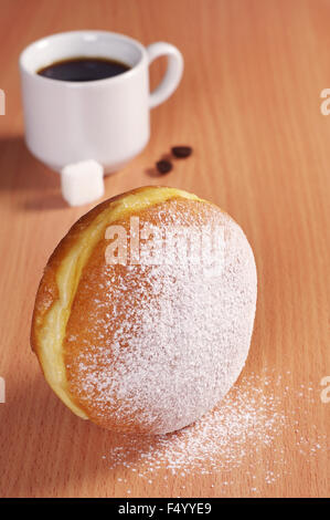 Berliner Krapfen mit Tasse heißen Kaffee am Schreibtisch Stockfoto