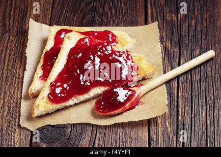 Zwei Scheiben toast Brot Himbeer Konfitüre auf alten Holztisch Stockfoto