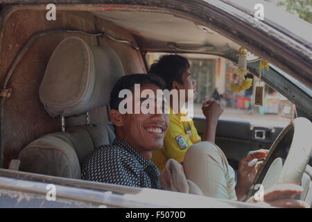 Asiatischer Mann am Lenkrad in seinem sehr alten Auto. Kontrast und Helligkeit angepasst Bild. Stockfoto