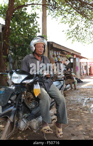 Reife asiatische Mann sitzt auf seinem Motorrad in Sisophon Kambodscha Stockfoto