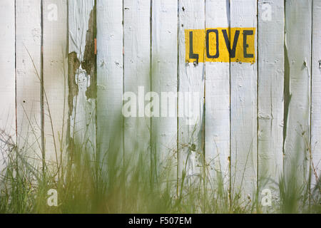 Das Wort "LOVE" geschrieben auf einem weiß getünchten Zaun Stockfoto