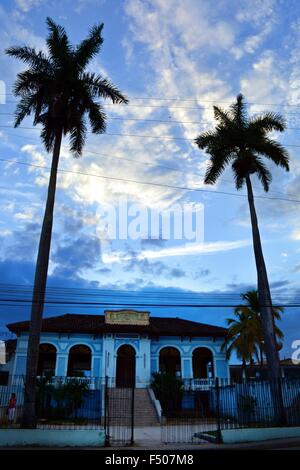 Palmen, die Silhouette gegen den Schein der Abendhimmel vor den Schultoren in Santa Clara, Kuba Stockfoto