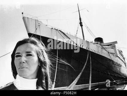 Eine angehende Studentin posiert vor Seawise University, dem ehemaligen RMS Queen Elizabeth, während sie in Port Everglades, Florida, USA 1971 angedockt wurde. Einmal die weltweit größte Passagierschiff, es war beabsichtigt, eine schwimmende Schule geworden, die den Globus gesegelt. Jedoch ein Jahr später der Ozeandampfer fing Feuer und sank im Hafen von Hong Kong Victoria während es wie eine schwimmende Campus für Studenten umgebaut wurde. Teile von 83.000-Tonnen-Schiff, die nicht geborgen wurden wurde eine Navigations Gefahr im Hafen bis mit Deponie in den späten 1990er Jahren begraben. Historisches Foto. Stockfoto