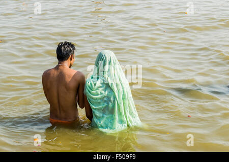 Junges Paar beten in das Wasser des Flusses Ganges am frühen Morgen an der sangam, dem Zusammenfluss von Ganges, Yamuna und s Stockfoto