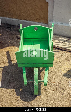 Nahaufnahme der alten hölzernen dekorative handgefertigte grüne Schubkarre. Stockfoto