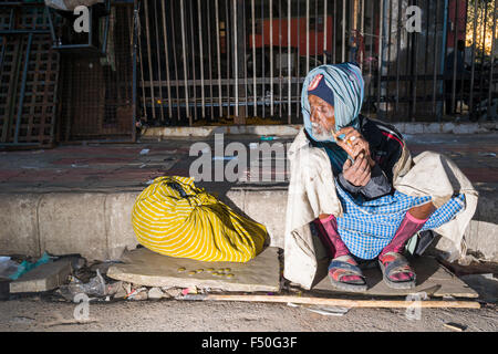 Eine obdachlose Bettler sitzt auf dem Bürgersteig, nachdem er die Nacht schläft auf dem Betonboden Stockfoto