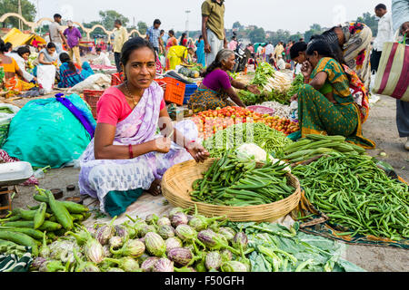 Eine Frau verkauft, Auberginen, Gurken, Blumenkohl und okras auf dem wöchentlichen Gemüsemarkt Stockfoto