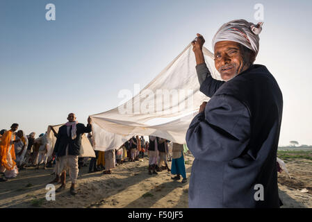 Ein männlicher Pilger, Mann, ist das Trocknen der Sari seiner Frau nach der Badewanne und betet im heiligen Fluss Yamuna Stockfoto