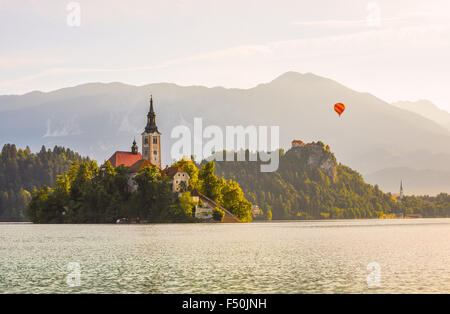 Berühmte katholische Kirche auf der kleinen Insel im Bled See und Bled Schloss auf einem Felsen in Slowenien mit Heißluftballon fliegen mit Moun Stockfoto