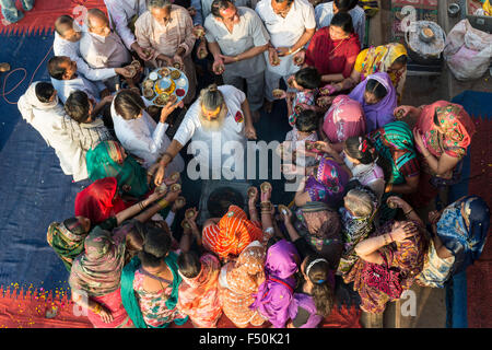 Ein Priester, Brahmane, ist Segen eine Gruppe von Pilgern auf der ghats am heiligen Fluss Yamuna, von oben gesehen Stockfoto