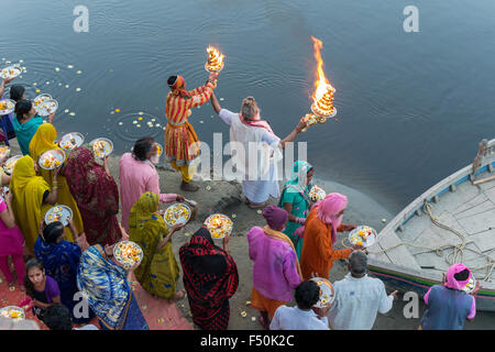 Ein Priester, der Brahmanen, und einige Pilger feiern ein Ritual, Pooja, an den ghats am heiligen Fluss Yamuna, von oben gesehen Stockfoto