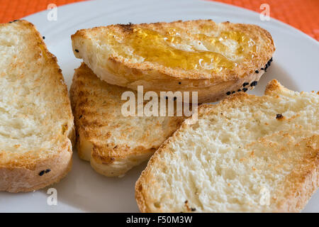 im Bild Scheibe Brot geröstet mit Honig auf weißem Teller im Restaurant. Stockfoto