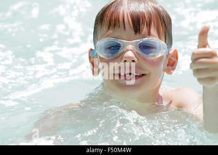 Kleiner Junge im Schwimmbad tragen Schutzbrillen geben Daumen nach oben Stockfoto