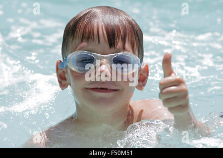 Kleiner Junge im Schwimmbad tragen Schutzbrillen geben Daumen nach oben Stockfoto