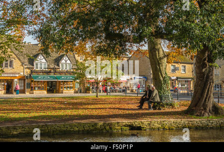 Bourton auf dem Wasser, einem ländlichen Dorf in den Cotswolds an einem sonnigen Herbsttag mit zwei Herren im Gespräch Stockfoto