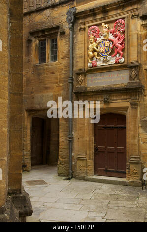 Einen kleinen abgelegenen Hof in Sherborne Schule. Über eine Tür befindet sich der königliche Wappen von König Edward 6.. Dorset, England. Stockfoto