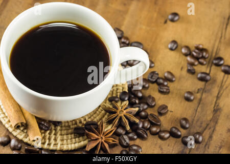 Kaffee in der Tasse mit Kaffeebohnen und Zimt klebt auf Holz Hintergrund, warmen Tönen, selektiven Fokus Stockfoto