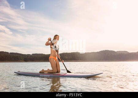 Schöne sportliche Frau Paddle boarding auf einem See in der Sonne Stockfoto