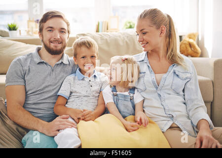 Happy Family im Casualwear sitzt zu Hause auf sofa Stockfoto