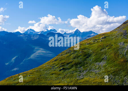 Landschaft mit Schnee bedeckten Bergen und grünen Berghang am Nufenenpass Stockfoto