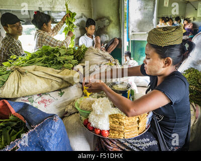 Yangon, Yangon Division, Myanmar. 26. Oktober 2015. Ein Lieferant stellt Nudeln Gerichte für Kunden auf den kreisförmigen Zug von Yangon. Die Yangon kreisförmigen Bahn ist das lokale Pendler Schienennetz, das das Stadtgebiet von Yangon dient. Von Myanmar Railways betrieben, verbindet die 45.9 Kilometer (28.5Â Meile) 39-Station-Loop-System Satellitenstädte und vorstädtischen Gebieten in die Stadt. Die Bahn hat rund 200 Trainer, 20 Mal täglich läuft und täglich 100.000 bis 150.000 Tickets verkauft. Die Schleife, die etwa drei Stunden dauert, ist ein beliebtes für Touristen zu sehen, einen Querschnitt des Lebens in Yangon. Die Züge Stockfoto