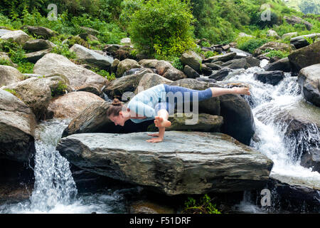 Junge passen Frau tut Yoga Oudoors am Wasserfall Stockfoto