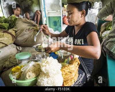 Yangon, Yangon Division, Myanmar. 26. Oktober 2015. Ein Lieferant stellt Nudeln Gerichte für Kunden auf den kreisförmigen Zug von Yangon. Die Yangon kreisförmigen Bahn ist das lokale Pendler Schienennetz, das das Stadtgebiet von Yangon dient. Von Myanmar Railways betrieben, verbindet die 45.9 Kilometer (28.5Â Meile) 39-Station-Loop-System Satellitenstädte und vorstädtischen Gebieten in die Stadt. Die Bahn hat rund 200 Trainer, 20 Mal täglich läuft und täglich 100.000 bis 150.000 Tickets verkauft. Die Schleife, die etwa drei Stunden dauert, ist ein beliebtes für Touristen zu sehen, einen Querschnitt des Lebens in Yangon. Die Züge Stockfoto