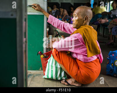 Yangon, Yangon Division, Myanmar. 26. Oktober 2015. Burmesische Nonne sitzt in der Tür der Yangon kreisförmigen Bahn. Die Yangon kreisförmigen Bahn ist das lokale Pendler Schienennetz, das das Stadtgebiet von Yangon dient. Von Myanmar Railways betrieben, verbindet die 45.9 Kilometer (28.5Â Meile) 39-Station-Loop-System Satellitenstädte und vorstädtischen Gebieten in die Stadt. Die Bahn hat rund 200 Trainer, 20 Mal täglich läuft und täglich 100.000 bis 150.000 Tickets verkauft. Die Schleife, die etwa drei Stunden dauert, ist ein beliebtes für Touristen zu sehen, einen Querschnitt des Lebens in Yangon. Die Züge verkehren von Stockfoto