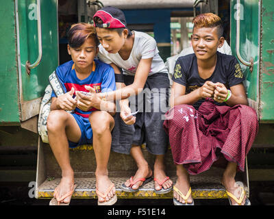 Yangon, Yangon Division, Myanmar. 26. Oktober 2015. Jugendliche schauen Sie sich ihre Smartphones auf den Yangon kreisförmigen Zug. Die Yangon kreisförmigen Bahn ist das lokale Pendler Schienennetz, das das Stadtgebiet von Yangon dient. Von Myanmar Railways betrieben, verbindet die 45.9 Kilometer (28.5Â Meile) 39-Station-Loop-System Satellitenstädte und vorstädtischen Gebieten in die Stadt. Die Bahn hat rund 200 Trainer, 20 Mal täglich läuft und täglich 100.000 bis 150.000 Tickets verkauft. Die Schleife, die etwa drei Stunden dauert, ist ein beliebtes für Touristen zu sehen, einen Querschnitt des Lebens in Yangon. Die Züge verkehren fr Stockfoto