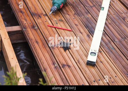 Bau einer Terrasse, Bohren, Maschine, Kapselheber, einen Stift und eine Wasserwaage auf ein Deck-Terrasse Stockfoto