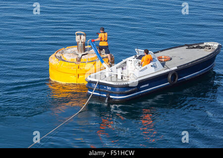 Ajaccio, Frankreich - 30. Juni 2015: Hafenbetrieb, Männer bei der Arbeit. Motorboot ist für Seilbefestigung auf gelben Anlegeboje verwendet. Stockfoto