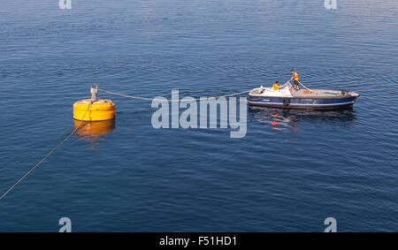 Ajaccio, Frankreich - 30. Juni 2015: Hafenbetrieb, Männer bei der Arbeit, kleines Boot dient zur Seilbefestigung auf große gelbe Anlegeboje Stockfoto