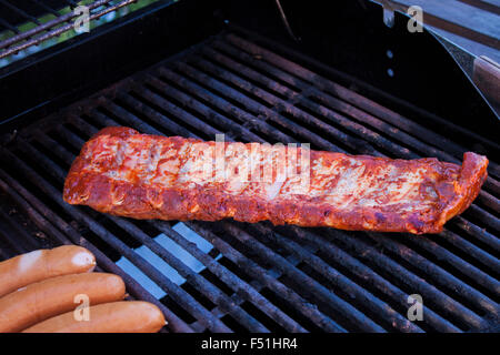 Lende Schweinerippchen, in der Nähe von Würstchen, auf einem Grill Stockfoto