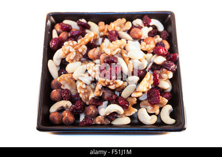 Nuss-Mix mit getrockneten Cranberries, auf einem schwarzen Teller, isoliert auf weißem Hintergrund Stockfoto