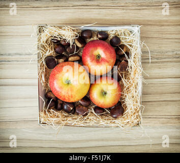 Drei Äpfel und Kastanien in der Box auf den hölzernen Hintergrund. Gesunde Ernährung. Stockfoto