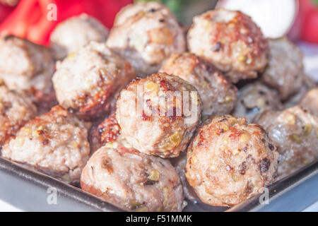 Ein Haufen von Frikadellen auf einer schwarzen Platte vor Gemüse Stockfoto