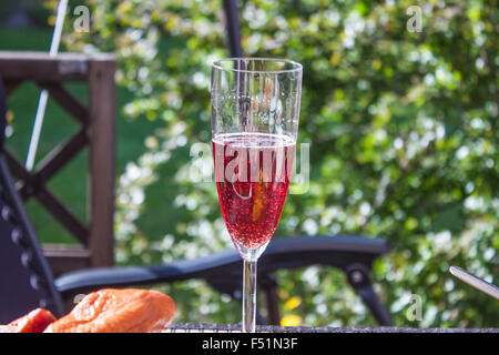 Ein Glas voll von roten rose Sekt am Grill Party Tisch Stockfoto