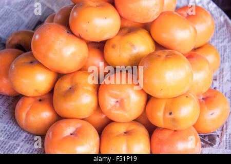 Eine Menge von Orage Diospyros Kaki, Kaki, auf einem Markt in Phu Quoc, Vietnam Stockfoto