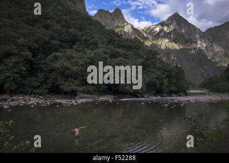 Ein Tourist badet im Fluss Urubamba neben Berg wo befindet sich die Stadt Machupicchu Stockfoto