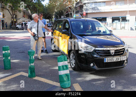 Zwei Personen werden von einem Taxi mit spanischen Kennzeichen in der Nähe von Sagrada de Familia in Barcelona abgesetzt. Stockfoto